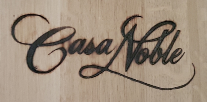 The name of Casa Noble burned into a tequila barrel