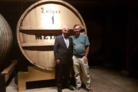 Costas Raptis and Mike Gerrard of Travel Distilled in front of Metaxa's Number One barrel at their distillery cellar in Athens, Greece