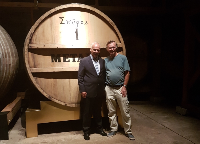 Costas Raptis and Mike Gerrard of Travel Distilled in front of Metaxa's Number One barrel at their distillery cellar in Athens, Greece