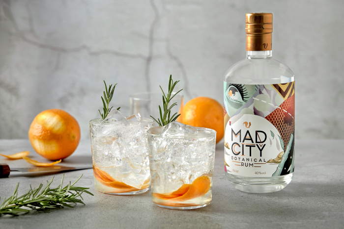 Bottle of Mad City Botanical Rum with a cocktail