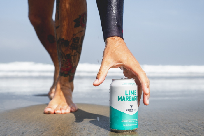 Cutwater Canned Cocktails Lime Margarita Beach with the hand of a surfer
