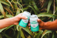 Two cans of Cutwater Canned Cocktails Lime Margarita clinking